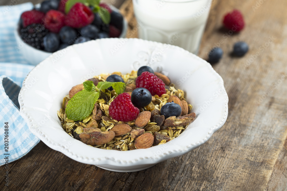 Fototapeta premium Homemade granola with fresh berries and mint, served with milk