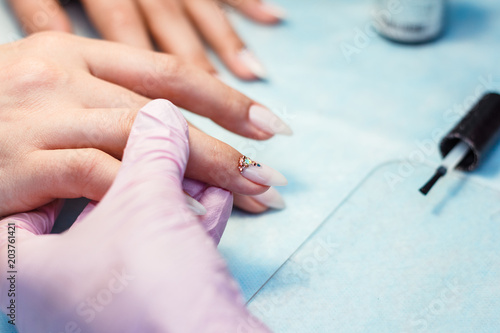 Close up manicure process. A professional manicurist glues rhinestones on nails