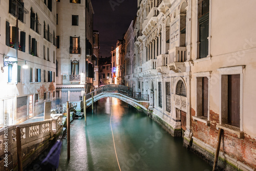 Night view of a typical canal in Venice with the light trail of a boat