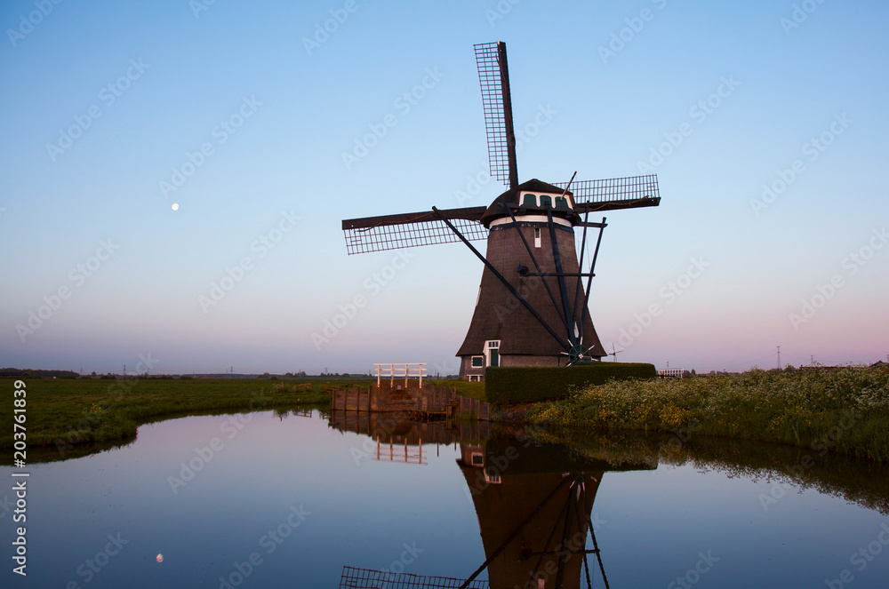 Sunrise with traditional Dutch windmills reflected in the calm w