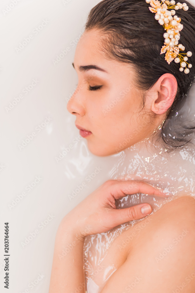Naklejka premium Closeup portrait of a young woman relaxing in the milk water