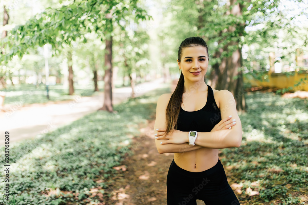 Beautiful and athletic girl with clothes for jogging standing with her hands crossed over her chest and looking at the camera in park Beautiful and athletic girl with clothes for jogging standing with her hands crossed over her chest and looking at the camera in park