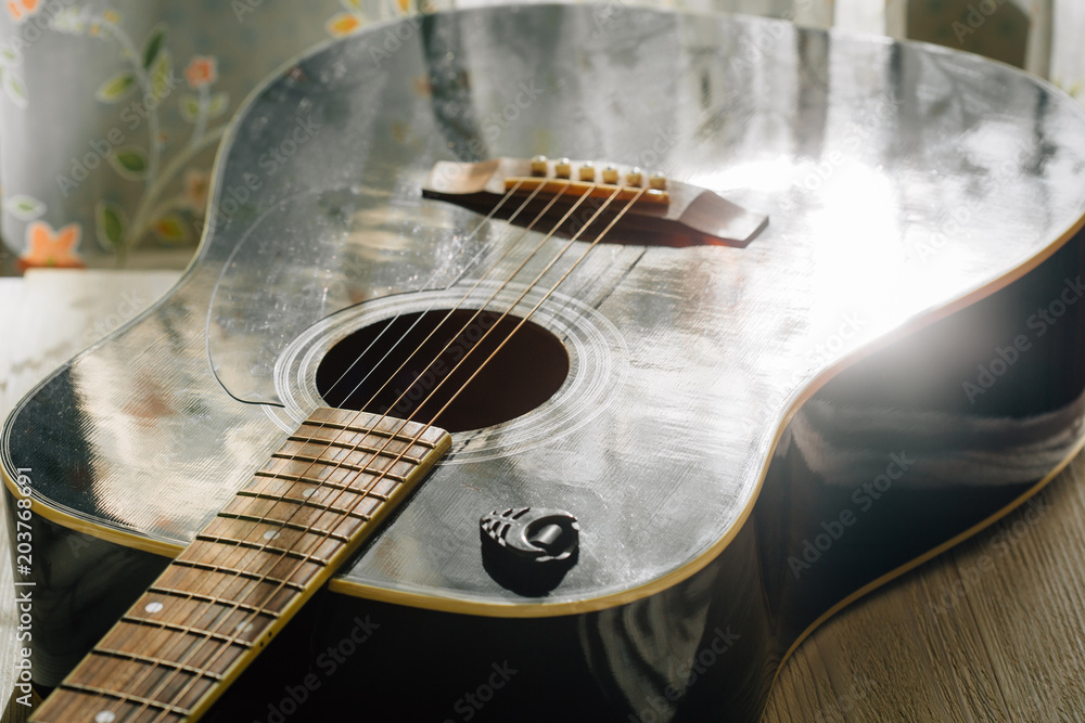 black acoustic guitar reflecting sun light