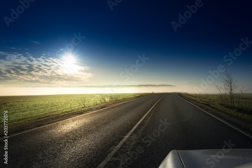 Summer Landscape with Field and Country Road Leading in the Fog. Dramatic Sky at Sunset Background. Beautiful Nature Background. photo