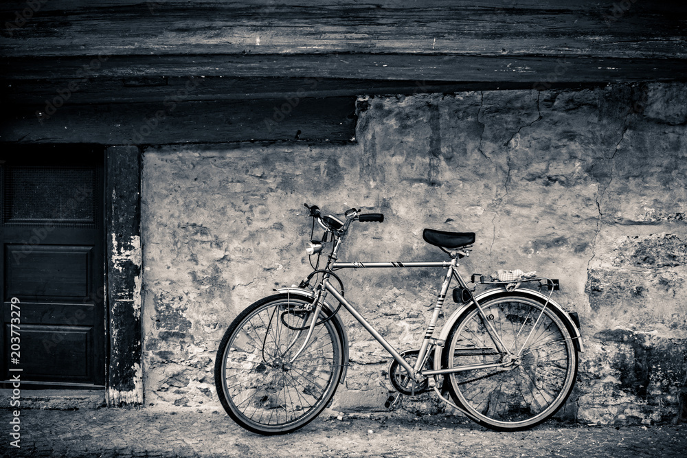 Modern bicycle standing on an old cobblestone covered street at a rugged stone wall