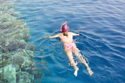 Snorkeling gear.  Snorkeling girl in full face mask.  Underwater swimming in Red sea near a coral reef. Tropical vacation activity snorkeling