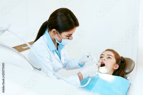 Stomatology. Dentist Working With Girl Teeth In Dental Clinic.