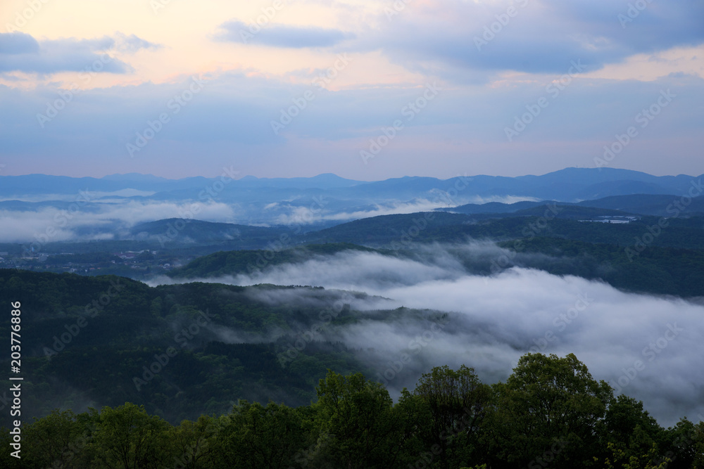 Morning fog drifts through low hills, seen from Takataniyama Camp Ground near Miyoshi, Japan