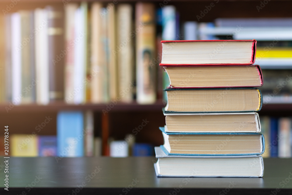 A stack of books on the background of bookshelves. A stack of books on the background of bookshelves.