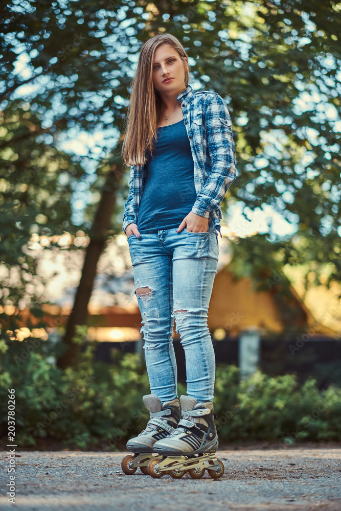 Obraz premium Portrait of a beautiful girl with long hair wearing fleece shirt and jeans in rollers, standing in the park in summer day.