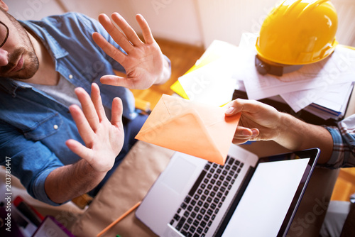Принти на полотні Young businessman is refusing a bribe in the envelope over the laptop from a contractor
