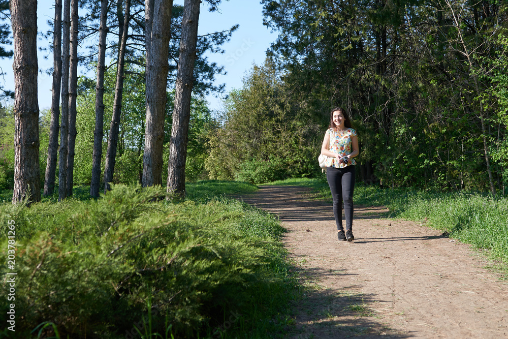 young girl walking in spring forest with camera and taking pictures young girl walking in spring forest with camera and taking pictures