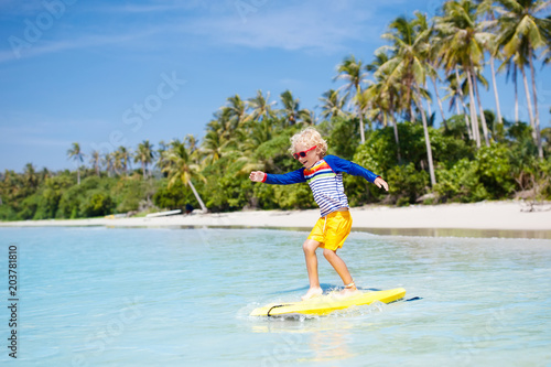 Photography Child surfing on tropical beach. Surfer in ocean.