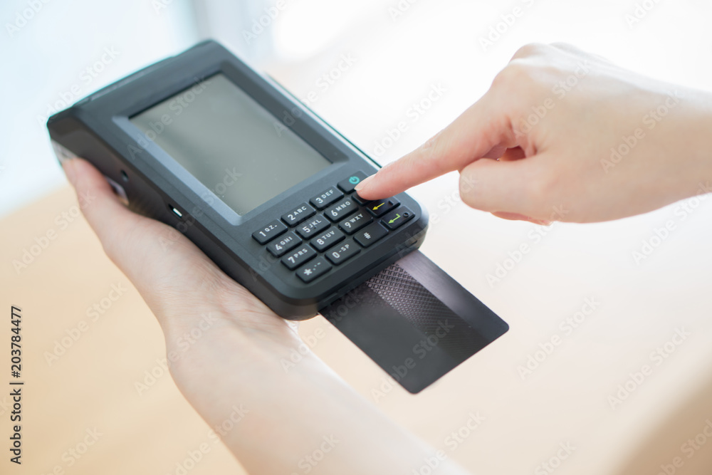 Hand with credit card swipe through terminal Hand with credit card swipe through terminal