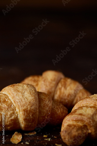 Tasty buttery croissants on an old wooden table, close-up, selective focus, shallow depth of field.