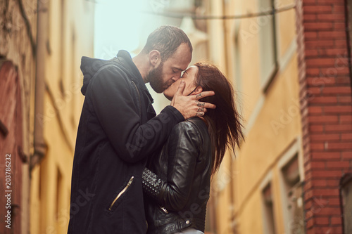 Bearded man and brunette girl kissing, on the background of the old European street.