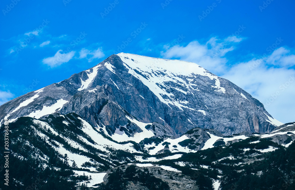 Obraz premium Mountain snow peak, beautiful natural winter backdrop. Ice top of the hill, blue sky background. Alpine forest landscape.