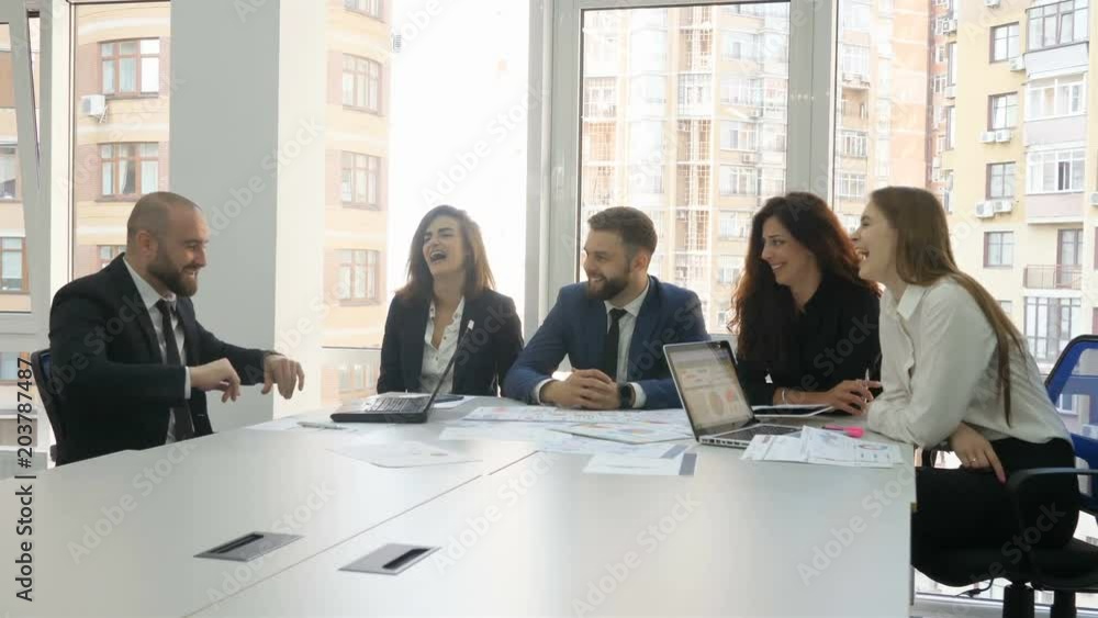 Office workers, employees of a large company, two young men and three young women discuss company issues, one of the men tells a funny story and everyone laughs, a moment of relaxation Office workers, employees of a large company, two young men and three young women discuss company issues, one of the men tells a funny story and everyone laughs, a moment of relaxation