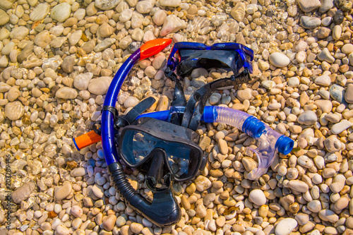 Snorkeling masks lying on a pebble beach. Summer vacation concept 