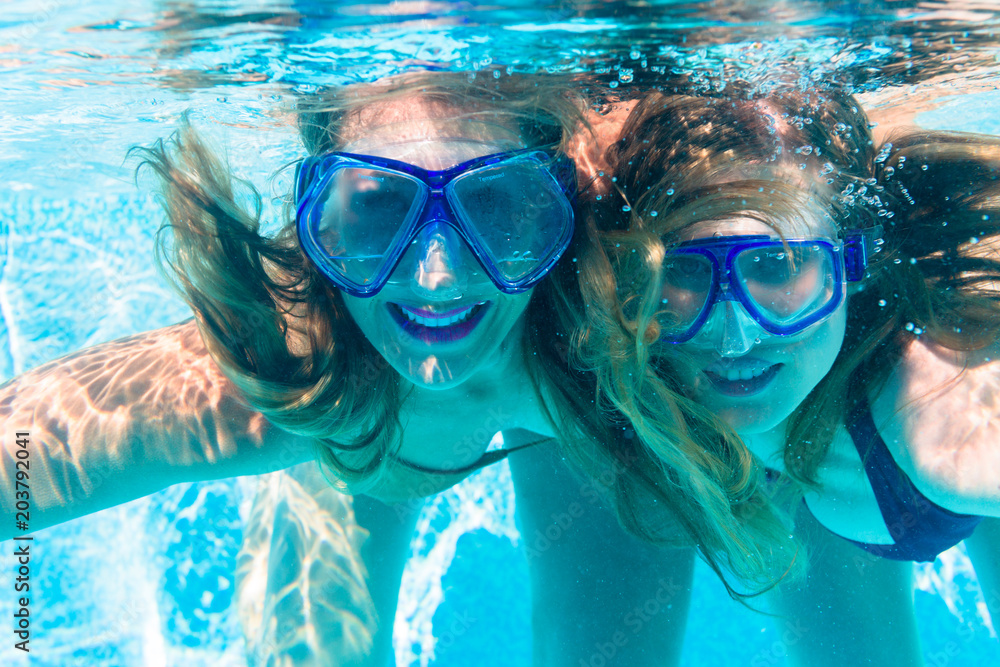 Girl friends diving underwater in resort swimming pool