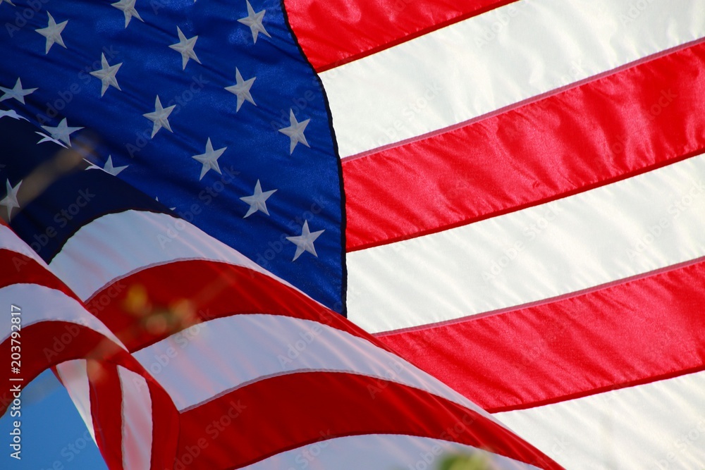 Obraz premium Close Up on American Flag Stars and Stripes Waving against Blue Sky Backlit by Afternoon Sun