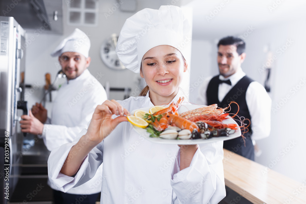 Woman chef of fish restaurant preparing dishes
