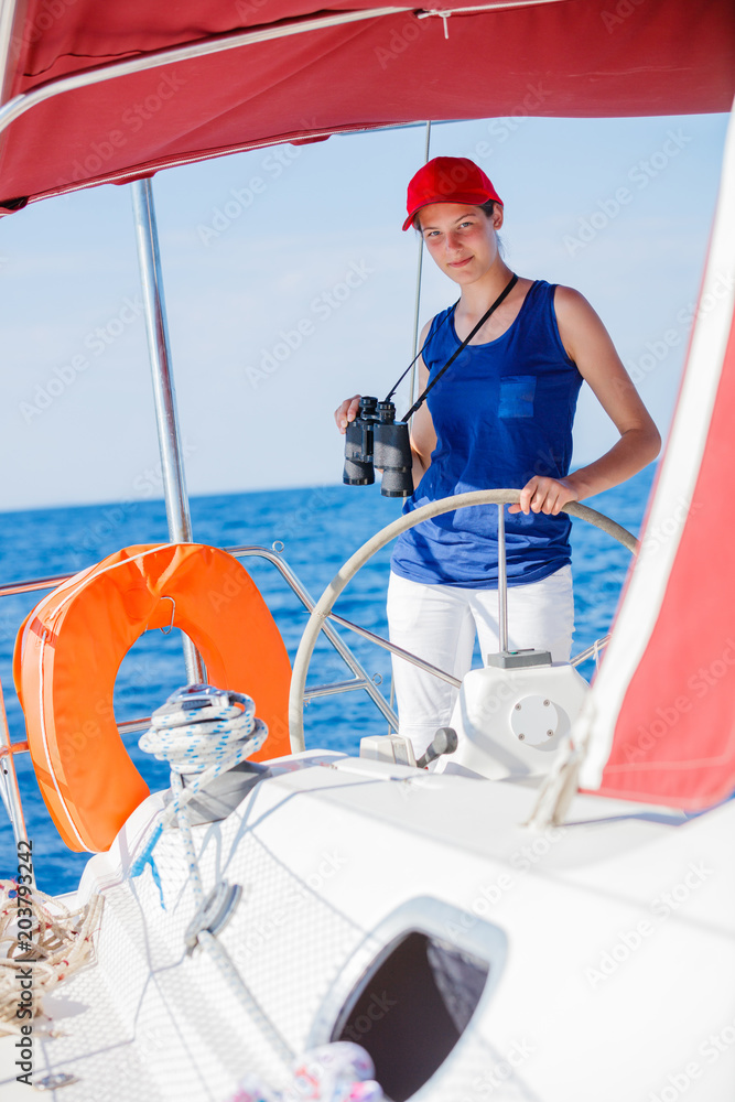 Girl captain on board of sailing yacht on summer cruise. Travel adventure, yachting with child on family vacation.