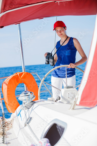 Girl captain on board of sailing yacht on summer cruise. Travel adventure, yachting with child on family vacation. © Max Topchii