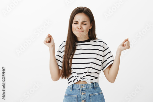 Girl is pissed off, trying to calm down. Annoyed angry beautiful european woman, raising clenched fists and frowning, puffling out cheeks, feeling outraged, trying to relaxed while feeling intense