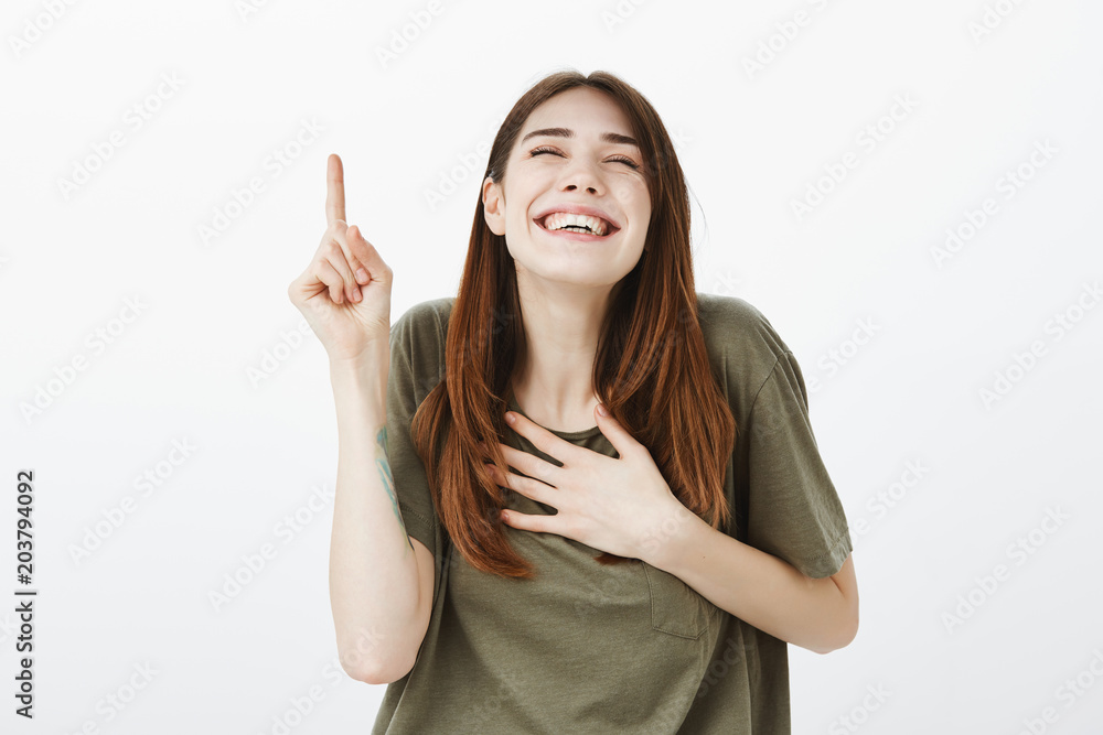 Portrait of over-emotive happy young woman in casual clothes, laughing out loud, holding hand on palm while raising index finger, showing number one or recalling funny moment from past Portrait of over-emotive happy young woman in casual clothes, laughing out loud, holding hand on palm while raising index finger, showing number one or recalling funny moment from past