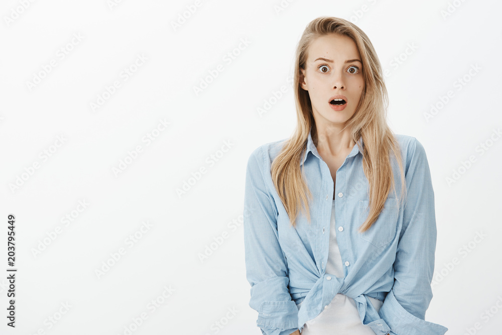 Waist-up shot of shocked european female coworker in stylish clothes, dropping jaw, saying wow and staring with popped eyes at camera, being stunned with curious revelation over gray background Waist-up shot of shocked european female coworker in stylish clothes, dropping jaw, saying wow and staring with popped eyes at camera, being stunned with curious revelation over gray background