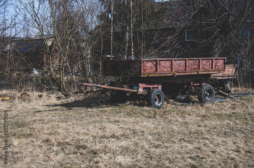 Old unused farm wagon trailer in the small village with old houses in Poland.