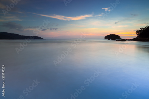 Sea at sunset.Seascape of smooth blurred blue sea water and small island at sunset with twilight sky and cloud long exposure photograph.