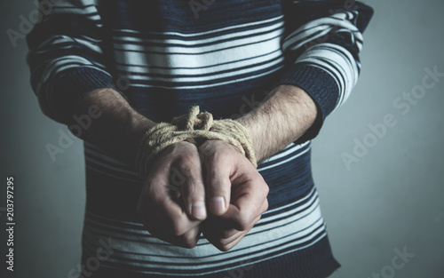 Male hands tied with a rope.