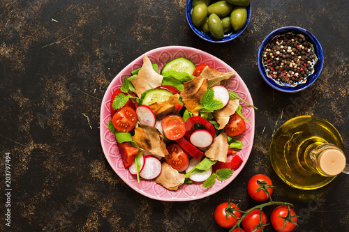 Salad of fresh vegetables with bread fattoush closeup. Arabic dish fattoush on a dark background, top view.