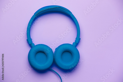 Blue headphones on empty purple background