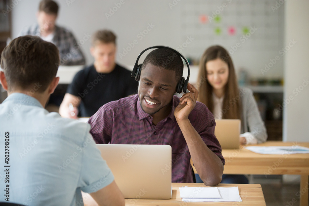 African american worker consulting client using wireless headset in modern coworking office. Black freelancer attentively watching webinar online. Concept of outsourcing, innovation, diverse work team African american worker consulting client using wireless headset in modern coworking office. Black freelancer attentively watching webinar online. Concept of outsourcing, innovation, diverse work team