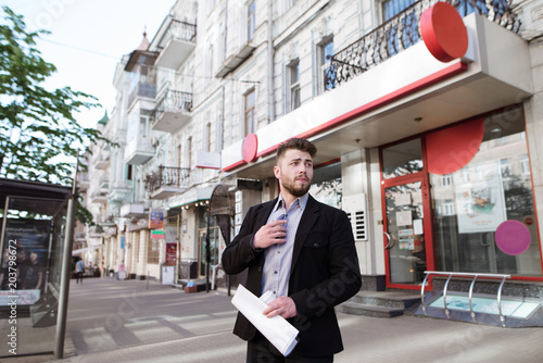 Portrait of a young banker with a beard at the bank. A businessman with documents in his hands is standing in the street at the entrance to the office photo