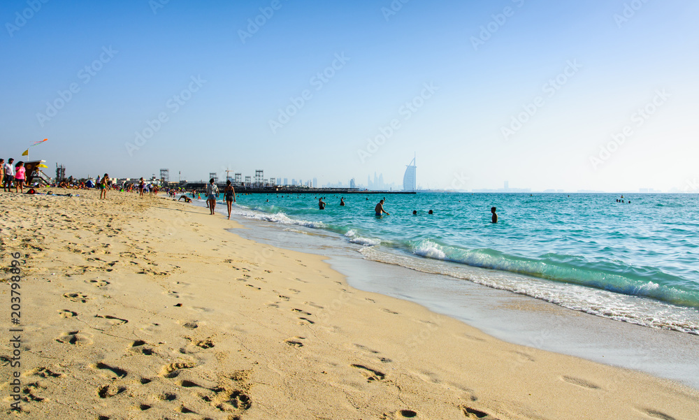 Dubai, United Arab Emirates, April 20, 2018: Kite beach in Dubai with many visitors and Burj Al Arab hotel in the background