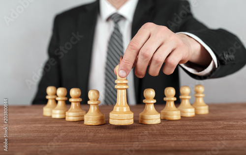 Businessman is moving chess figure of a king . Concept of business strategy.