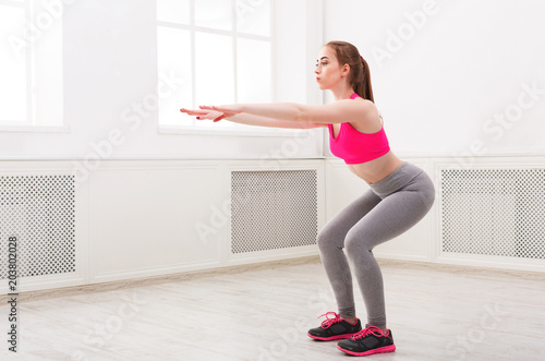 Fitness woman doing squat on white background