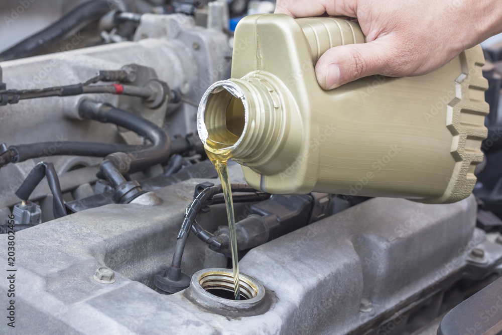Fototapeta premium car worker changes, adds oil in avto. Concept maintenance car repair