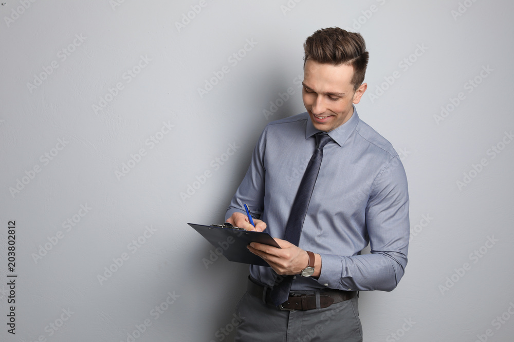 Male real estate agent with clipboard on grey background Male real estate agent with clipboard on grey background