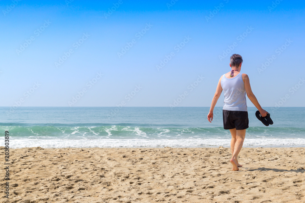 Old woman is walking on the beach and going to the sea in summer holiday vocation Old woman is walking on the beach and going to the sea in summer holiday vocation