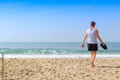 Old woman is walking on the beach and going to the sea in summer holiday vocation © flyalone