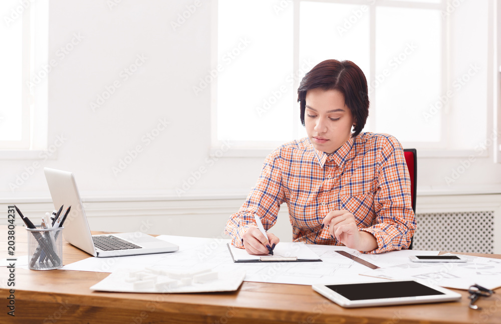 Young architect working with blueprints in the office