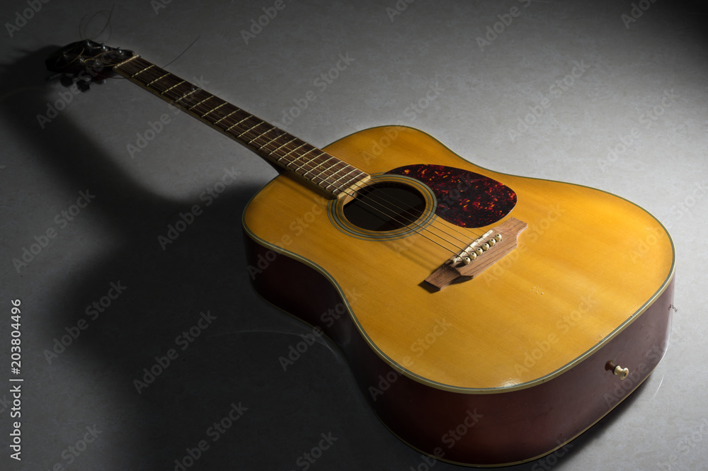 Wooden acoustic guitar on floor.