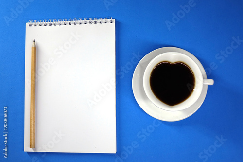 Notepad and coffee on colored background top view