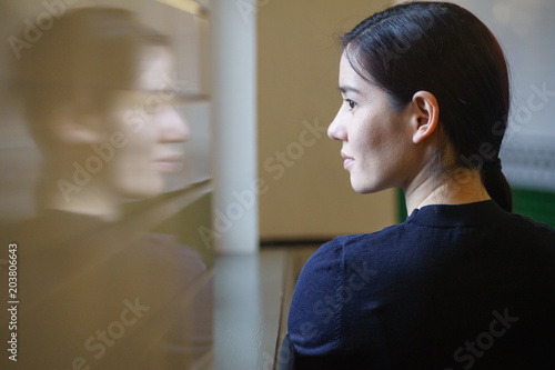 Indoor portrait of young beautiful model of mixed race dressed in black dress standing at the corridor with green tiles