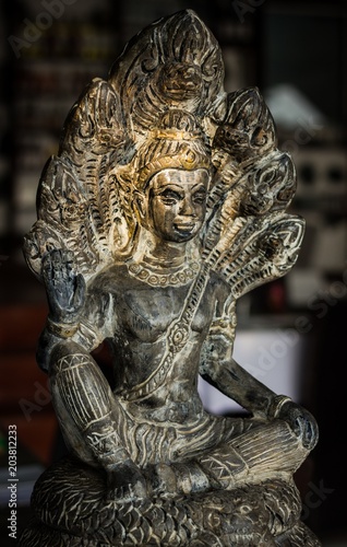 Buddha gray statue with seven head snakes naga to protect with warm sunset light on Buddha's face